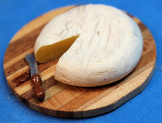 Brie cheese on wood board with knife